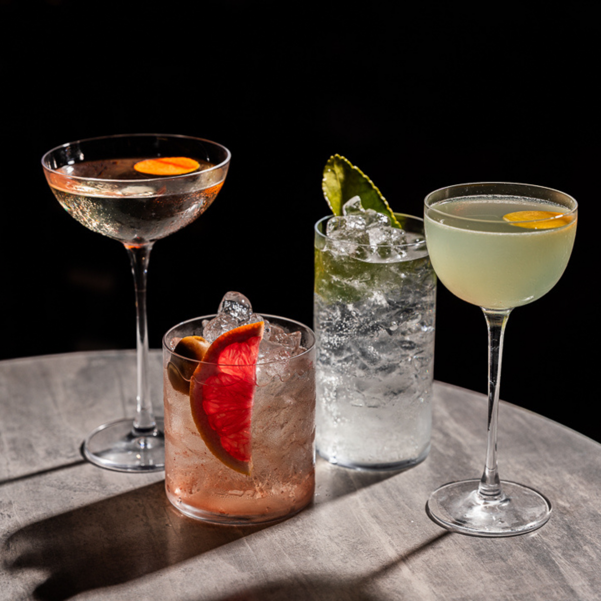 Four cocktails made from rakija liquor: Black Seas in a coupe glass, Rakija and Tonic in a short glass, Leto Spritz in a tall glass, and European Calling in a Nick & Nora glass