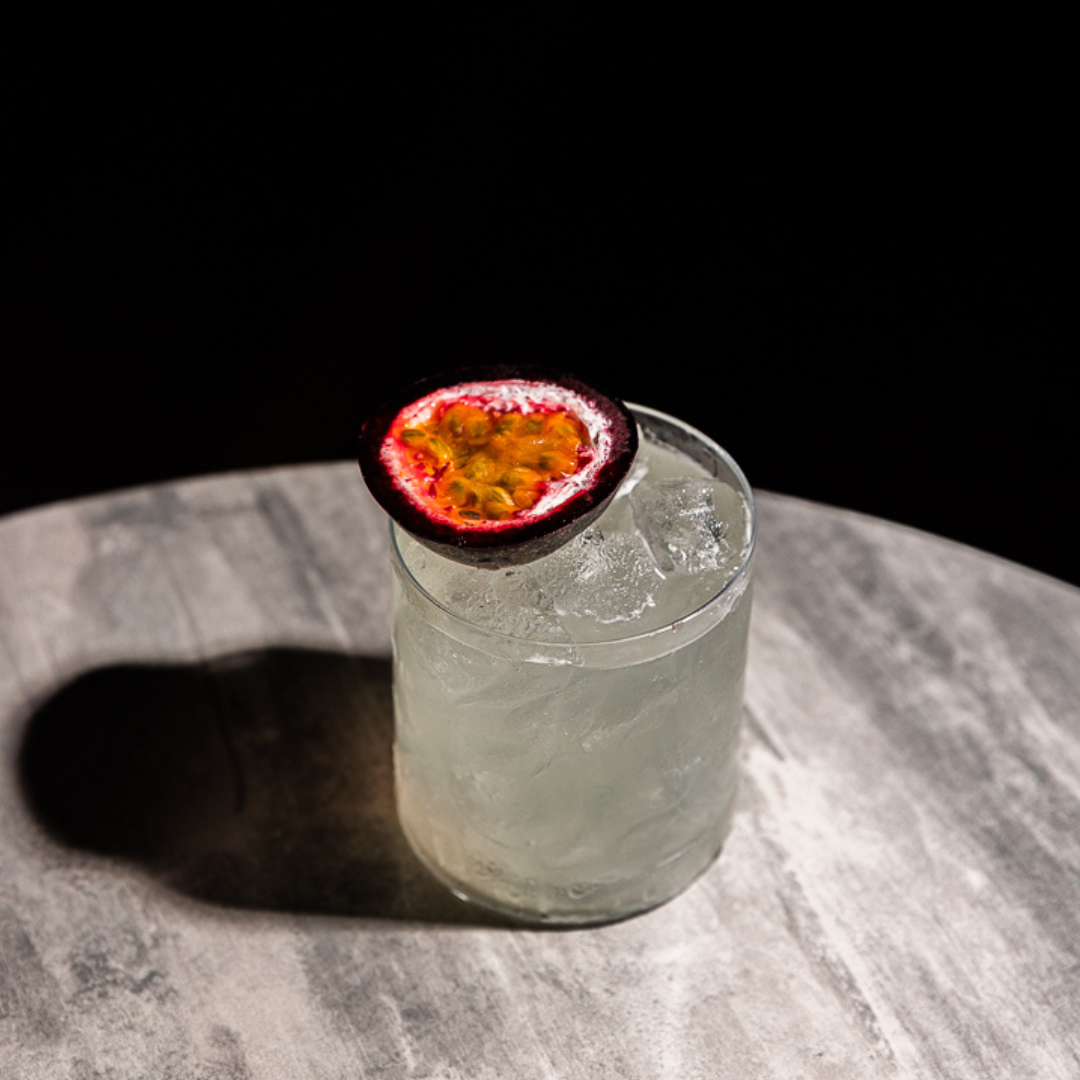 The Rakija Hardshake in a short glass, garnished with a piece of passionfruit