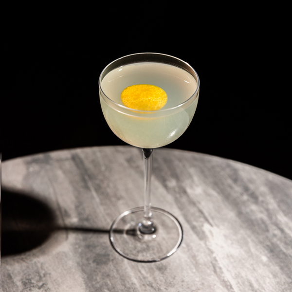 The Kiss Kiss Bang Bang is a cocktail variation of both a Mai Tai and a classic sour using rakija, served in a Nick & Nora glass and garnished with a lemon twist